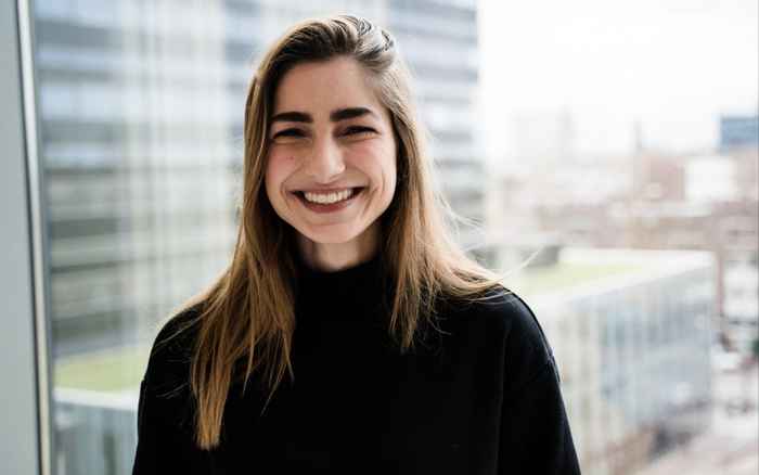 Student in dark shirt with a blurred building in the background